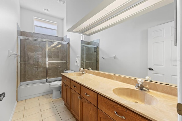 full bath featuring toilet, tile patterned floors, double vanity, and a sink