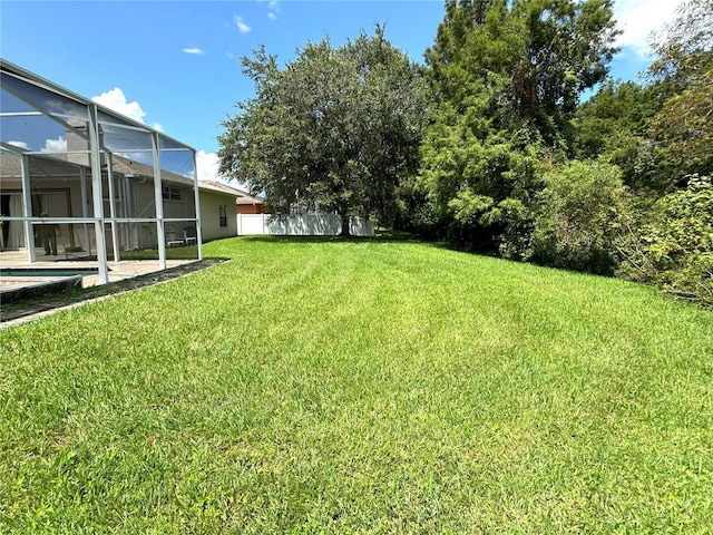 view of yard featuring fence, a patio area, an outdoor pool, and a lanai