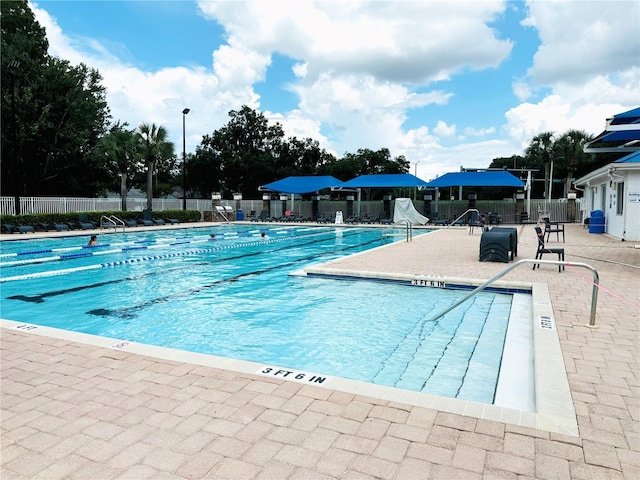 community pool with a patio area and fence