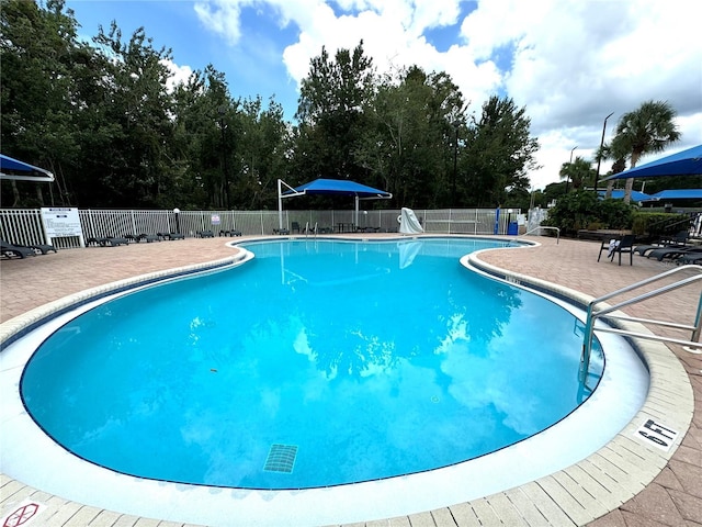 community pool with a patio and fence