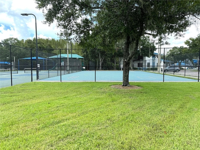 view of sport court featuring a yard and fence