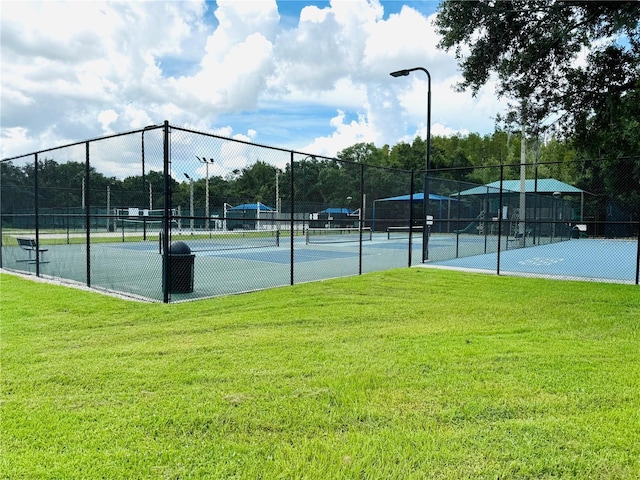 view of tennis court with fence and a lawn
