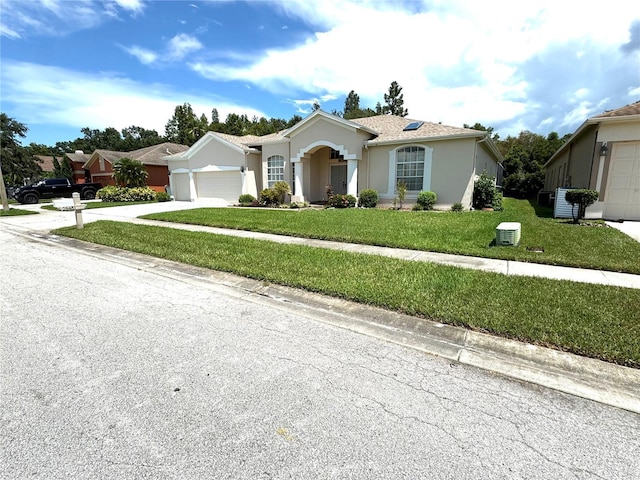single story home featuring a front yard, driveway, a garage, and stucco siding