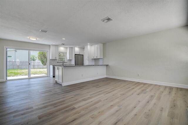 3841 Wahoo Dr SE, Saint Petersburg, FL 33705 - kitchen with light wood-style flooring, white cabinetry, visible vents, open floor plan, and baseboards