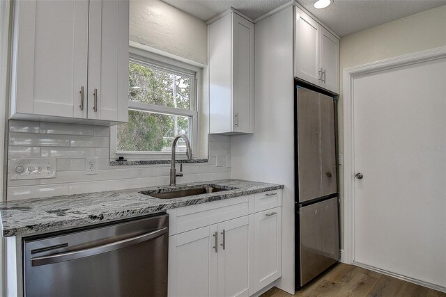 3841 Wahoo Dr SE, Saint Petersburg, FL 33705 - kitchen with tasteful backsplash, a sink, white cabinetry, and stainless steel appliances