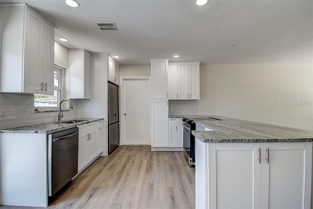 3841 Wahoo Dr SE, Saint Petersburg, FL 33705 - kitchen with light wood-type flooring, a peninsula, backsplash, appliances with stainless steel finishes, and a sink