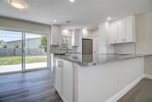 3841 Wahoo Dr SE, Saint Petersburg, FL 33705 - kitchen with baseboards, stainless steel fridge, a peninsula, dark wood-type flooring, and decorative backsplash