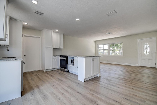 3841 Wahoo Dr SE, Saint Petersburg, FL 33705 - kitchen with visible vents, white cabinets, light wood-type flooring, and a textured ceiling