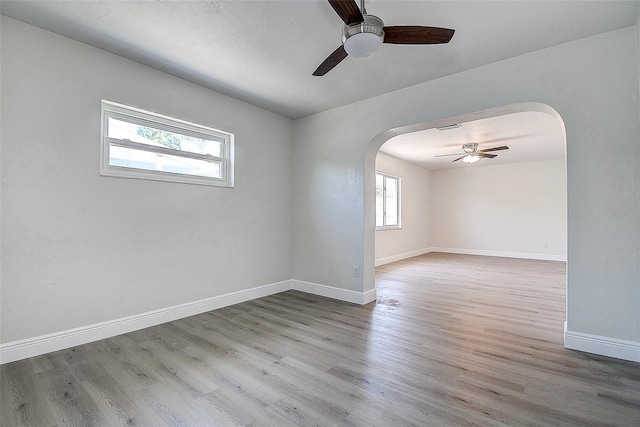 3841 Wahoo Dr SE, Saint Petersburg, FL 33705 - empty room with baseboards, a ceiling fan, arched walkways, and wood finished floors