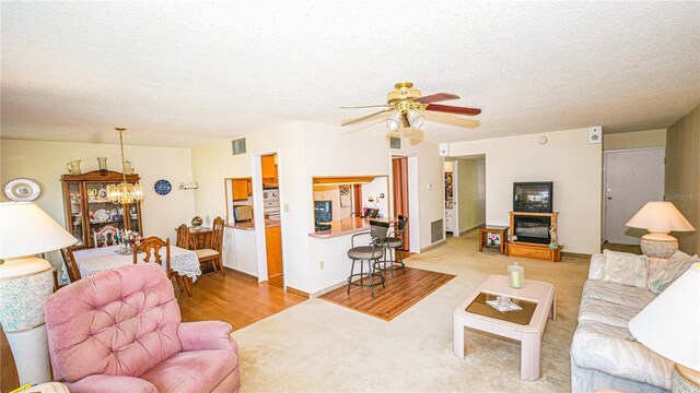 1655 S Highland Ave Unit F126, Clearwater, FL 33756 - living area with a textured ceiling, ceiling fan with notable chandelier, wood finished floors, and visible vents