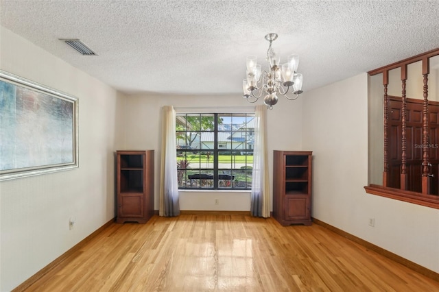 170 Foxfire Ln, Oldsmar, FL 34677 - unfurnished dining area with a chandelier, a textured ceiling, light wood-style flooring, and visible vents