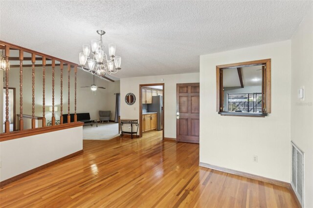 170 Foxfire Ln, Oldsmar, FL 34677 - interior space featuring visible vents, baseboards, light wood-style flooring, a textured ceiling, and ceiling fan with notable chandelier