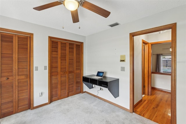 170 Foxfire Ln, Oldsmar, FL 34677 - bedroom featuring multiple closets, visible vents, a ceiling fan, light carpet, and baseboards