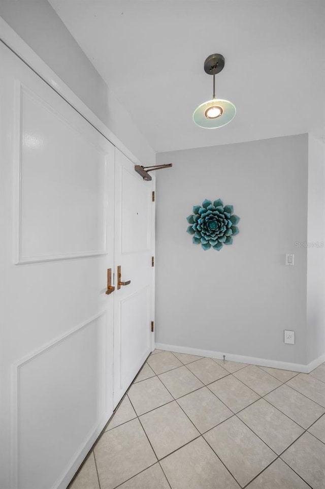 corridor with baseboards and light tile patterned flooring