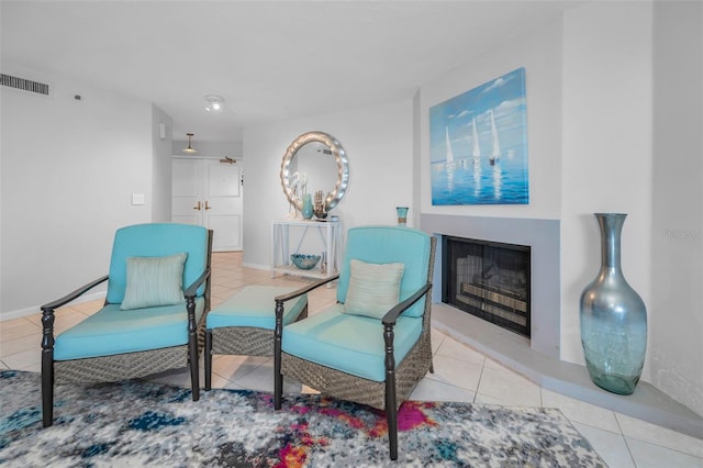 sitting room featuring a fireplace, tile patterned flooring, visible vents, and baseboards
