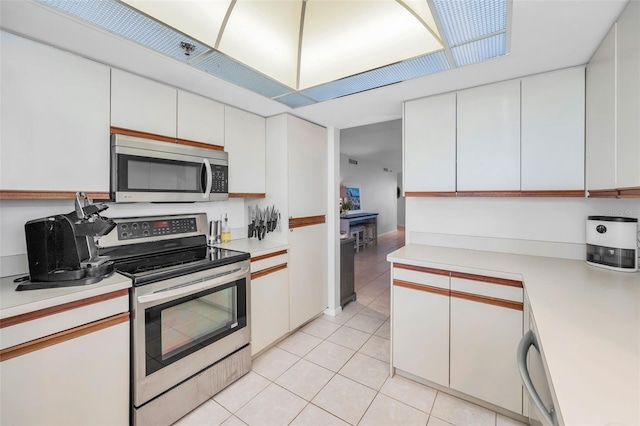 kitchen with light tile patterned flooring, light countertops, white cabinets, and stainless steel appliances