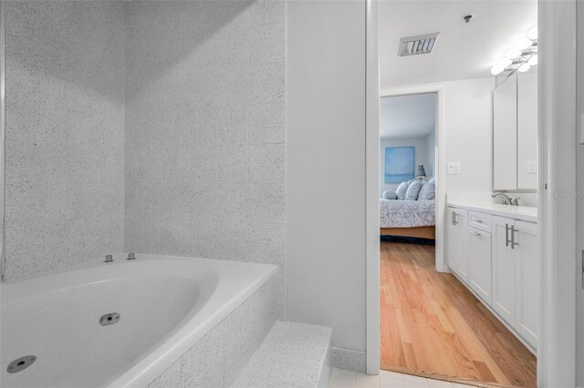bathroom featuring visible vents, connected bathroom, vanity, wood finished floors, and a garden tub
