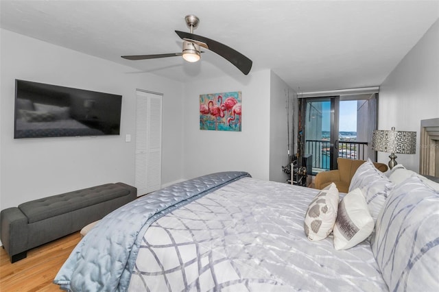 bedroom featuring access to outside, wood finished floors, a closet, and a ceiling fan