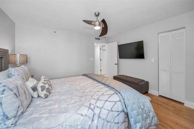 bedroom featuring visible vents, baseboards, a closet, a ceiling fan, and wood finished floors