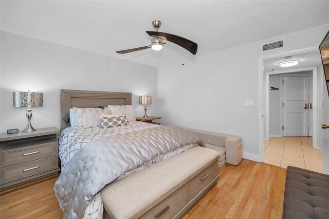 bedroom featuring visible vents, baseboards, a ceiling fan, and light wood-style floors