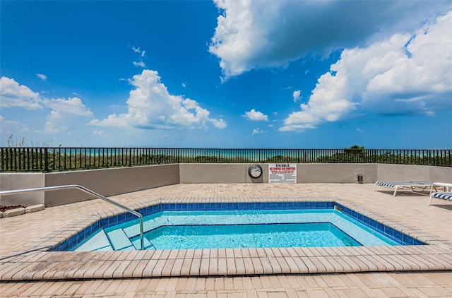 view of swimming pool with a patio, fence, and a water view