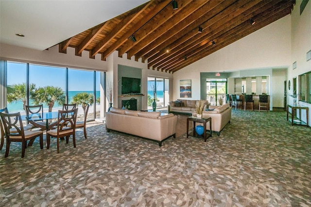 living area with high vaulted ceiling, carpet flooring, and beamed ceiling