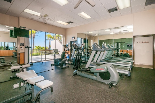 exercise room with a paneled ceiling, a ceiling fan, and visible vents