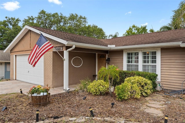 single story home with a garage, a shingled roof, and brick siding