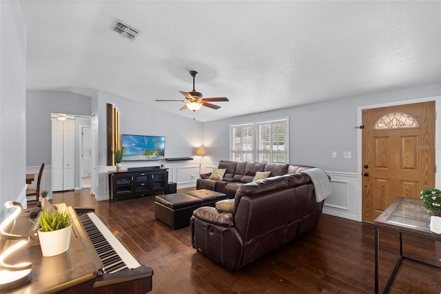 living room featuring a ceiling fan, dark wood finished floors, a decorative wall, vaulted ceiling, and a wainscoted wall