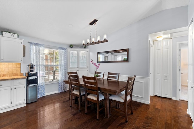 dining room featuring dark wood-style flooring, a chandelier, and a wainscoted wall