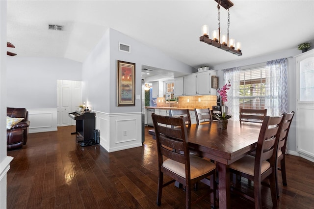 dining room with dark wood-style flooring, vaulted ceiling, and a wainscoted wall