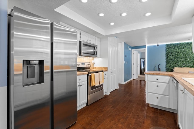 kitchen featuring appliances with stainless steel finishes, a raised ceiling, white cabinets, light countertops, and a textured ceiling