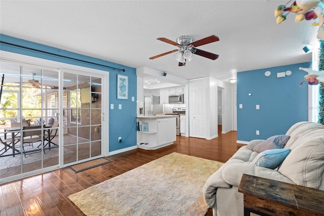 living area with a ceiling fan, dark wood-style flooring, and baseboards