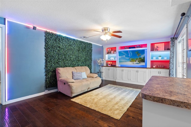 living area with dark wood-style flooring, a ceiling fan, a textured ceiling, and baseboards