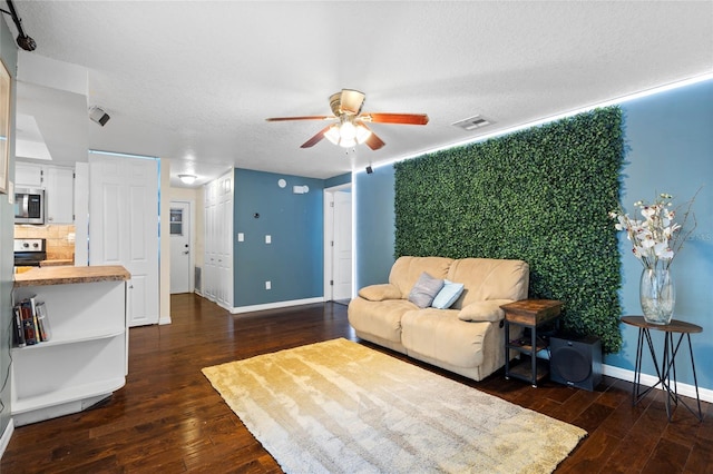 living room with dark wood finished floors, a ceiling fan, baseboards, and a textured ceiling
