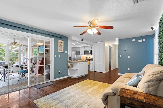 living room featuring a ceiling fan, baseboards, dark wood-style flooring, and a textured ceiling