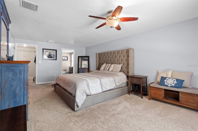 carpeted bedroom with connected bathroom, ceiling fan, and a textured ceiling