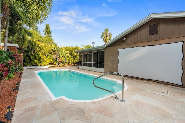 swimming pool with a sunroom and a patio area