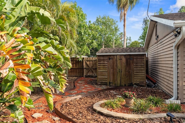 view of yard with a storage shed, fence, an outbuilding, and a gate