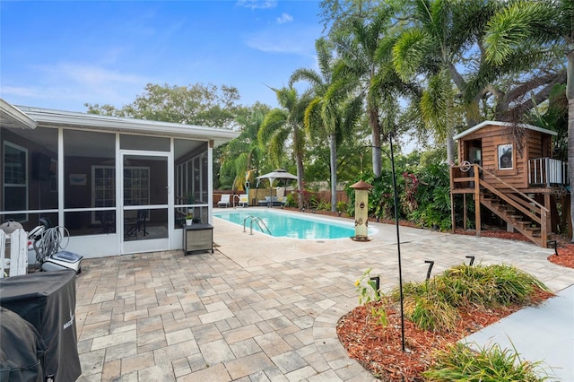 view of swimming pool featuring a sunroom and a patio area