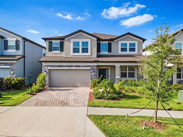 view of front of property with stucco siding, decorative driveway, stone siding, a front lawn, and a garage