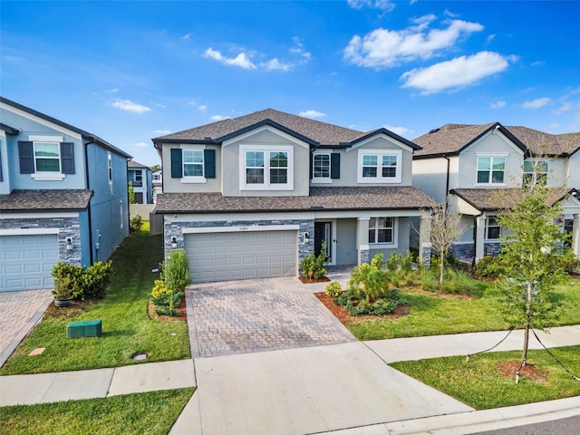 view of front of home featuring stucco siding, decorative driveway, a front yard, stone siding, and an attached garage