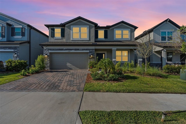 view of front of home featuring stucco siding, stone siding, decorative driveway, and an attached garage