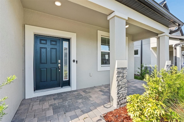 doorway to property featuring a porch and stucco siding
