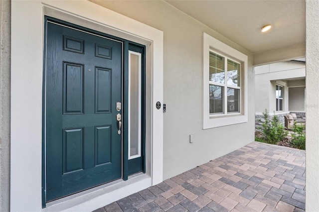 property entrance with stucco siding and covered porch