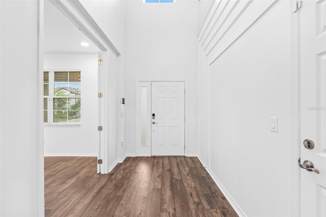 foyer entrance with a high ceiling, baseboards, dark wood finished floors, and visible vents