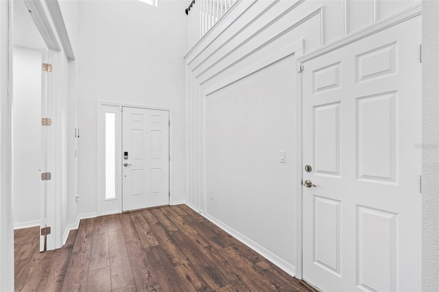 foyer entrance featuring a high ceiling, baseboards, and dark wood-style floors