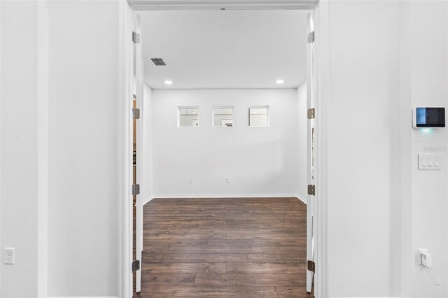 corridor featuring wood finished floors, baseboards, visible vents, and recessed lighting