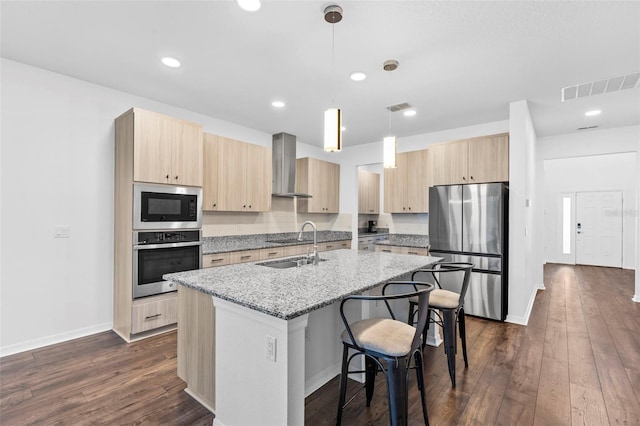 kitchen featuring light brown cabinets, wall chimney range hood, visible vents, and stainless steel appliances