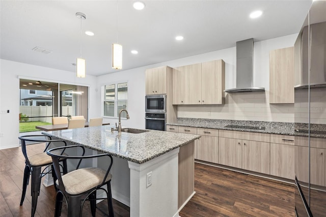 kitchen with light brown cabinetry, a sink, wall chimney exhaust hood, and stainless steel appliances